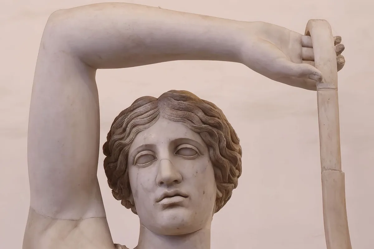 A classical marble statue head beneath a raised marble arm