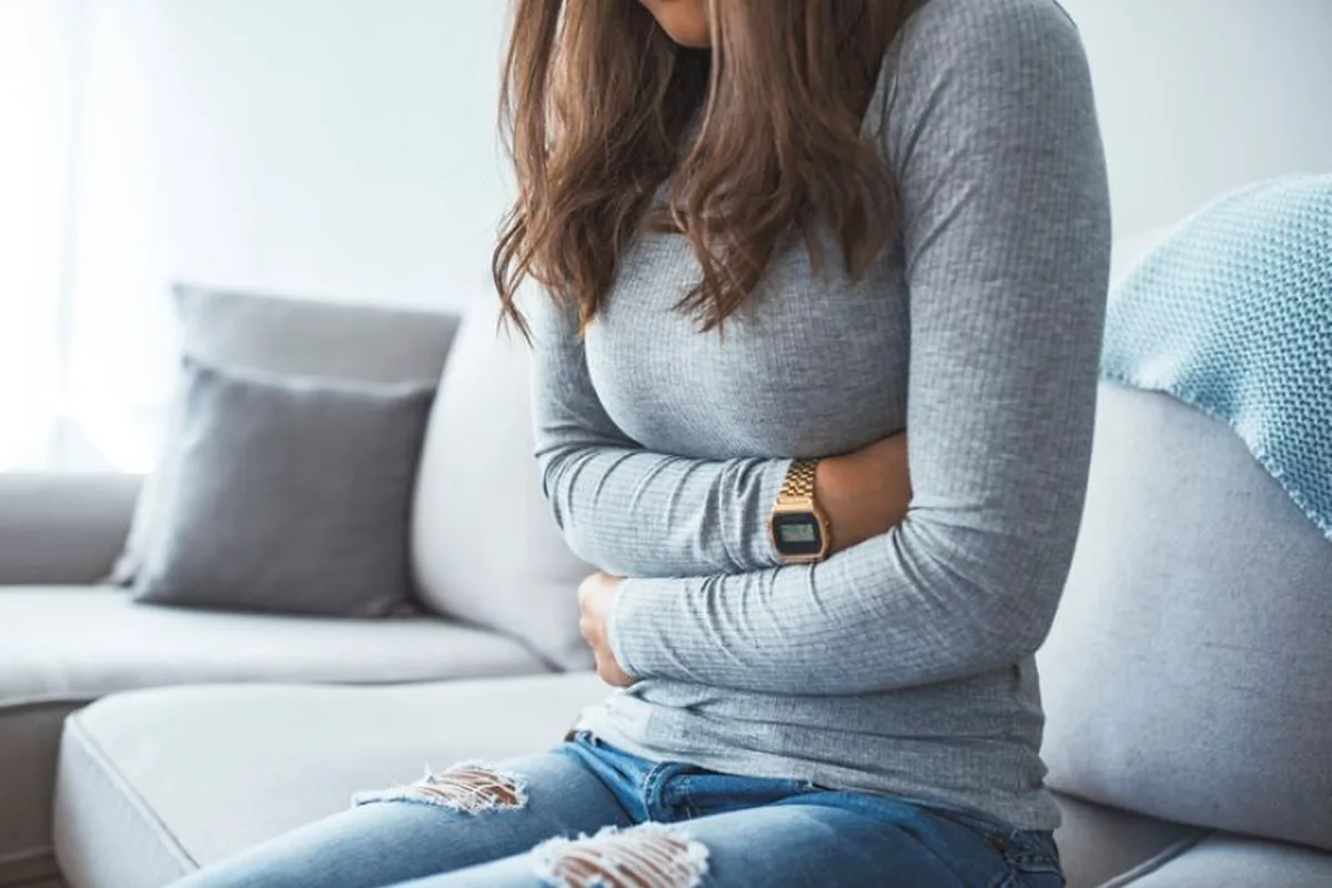 A woman sitting on a sofa holding her stomach